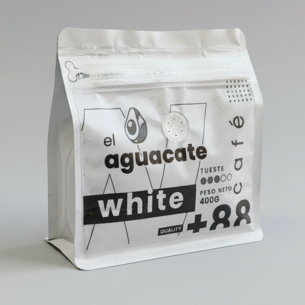Bolsa de café de especialidad El Aguacate White 400g con válvula desgasificadora sobre mesa de madera